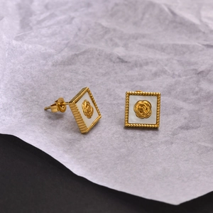 Détail de boucles d'oreilles carrées dorées avec rose en relief et incrustation nacre