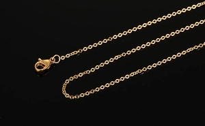 Détail de la chaîne dorée de 1mm avec fermoir mousqueton sur fond noir miroir réfléchissant