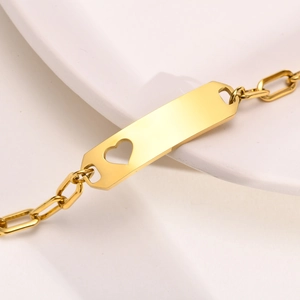 Goldenes Edelstahl-Armband mit Herz-Ausschnitt und Paperclip-Kette auf weißer Keramik