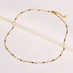 Detail of gold chain necklace featuring black and white beads with adjustable lobster clasp