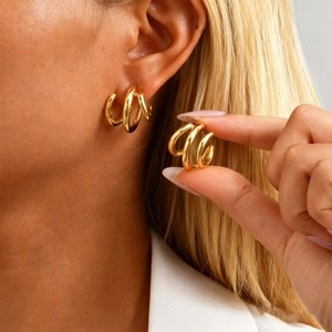 Gros plan sur des boucles d'oreilles à trois anneaux dorés portées avec élégance