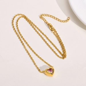 Detail of gold heart pendant with pink crystal and lobster clasp on cable chain