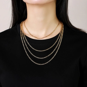 Detail of four-layered gold Figaro chains in different lengths worn over a black shirt