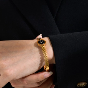 Detail of elegant gold watch with black dial and LOVE logo on model wearing black suit