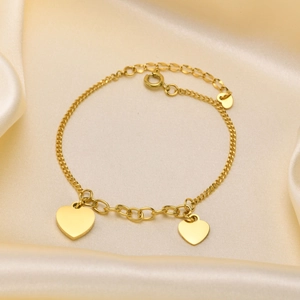 Elegant gold titanium steel bracelet with two heart pendants on cream silk background