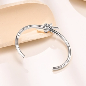 Dettaglio macro del nodo su un bracciale rigido aperto in acciaio inossidabile lucido