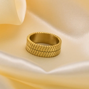 Minimalistischer Ring aus Titanstahl mit Goldschuppentextur auf Champagner-Seidenhintergrund