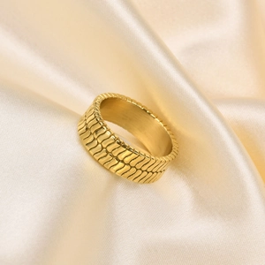 Nahaufnahme des goldenen Titanstahl-Rings mit Fischschuppenmuster auf Champagner-Satin