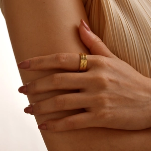 Detailaufnahme von goldenem Titanstahlring mit Schlangenschuppenstruktur am Finger