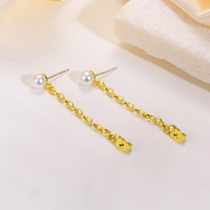 Orecchini pendenti dorati con perle su sfondo di pietra bianca per un look minimalista
