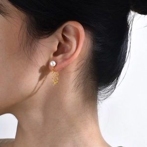 Orecchini a goccia vintage con perla e catena dorata indossati da una modella in primo piano
