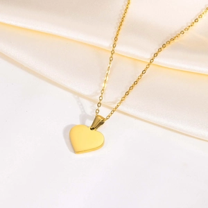 Polished heart shell pendant necklace in gold finish on smooth silk background