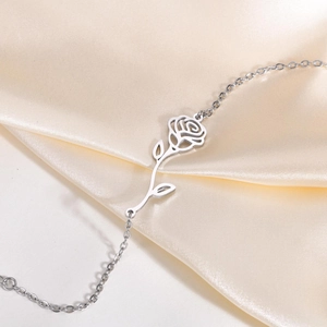 Macro shot of a stainless steel rose pendant on a fine link chain over silk
