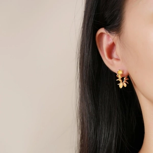 Dettaglio degli eleganti orecchini a fiore dorati indossati da una modella reale