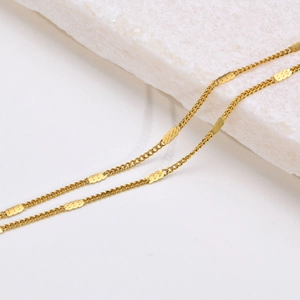 Minimalistische gouden titanium stalen ketting met golvende schakels op witte steen