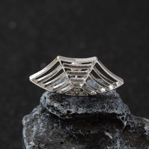 Macro detail of punk spider web earring on volcanic rock with metal texture focus