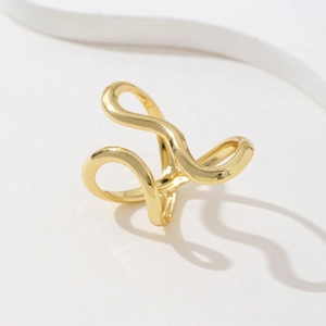 Macro shot of minimalist gold wave-shaped ring with abstract curved lines on white background