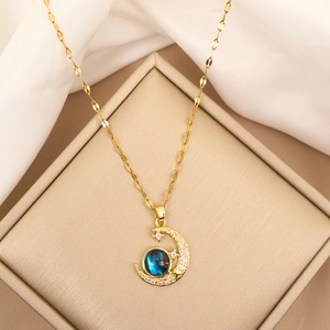 Detail van de gouden maan hanger met blauwe sterrensteen en fonkelende pavé kristallen