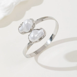 Macro detail of silver adjustable cuff bracelet featuring two baroque pearls at the ends