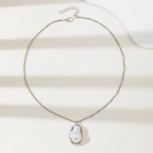Elegant irregular faux pearl pendant necklace with silver metal chain on ivory background