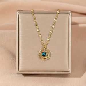 Close-up of Saturn-shaped necklace with deep blue orb and pave crystals in a jewelry box