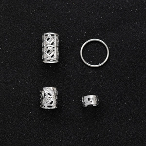 Macro shot of silver hollow-out hair cuffs and rings on black shimmering surface
