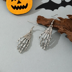 Gothic silver skeleton hand earrings on festive Halloween background with pumpkins