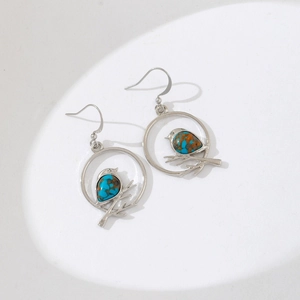 Silver bird on branch drop earrings with marble turquoise stones on white background