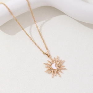Gold sun pendant necklace with moon and star design on a white display stand