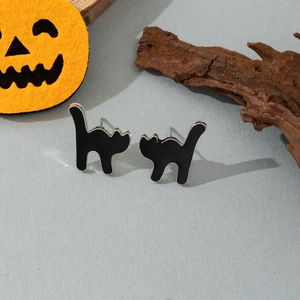 Detail view of black cat silhouette earrings with Halloween pumpkin and wood decor