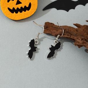 Close-up of black bat dangle earrings hanging on rustic wood for Halloween decor