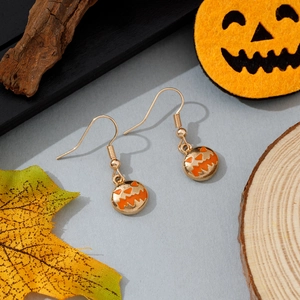 Gros plan sur des boucles d'oreilles citrouille d'Halloween avec émail orange vif