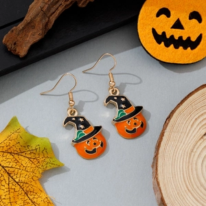 Détail de boucles d'oreilles citrouille d'Halloween avec chapeau sur fond de feuilles d'automne