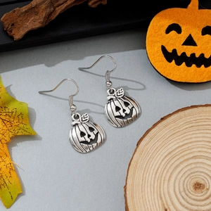 Vintage ασημένια σκουλαρίκια κολοκύθας Halloween σε ρουστίκ ξύλο και φθινοπωρινά φύλλα