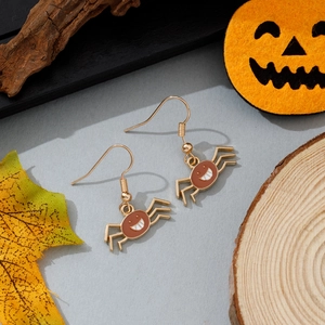 Gros plan de boucles d'oreilles araignée avec finition rouge sur décor d'Halloween
