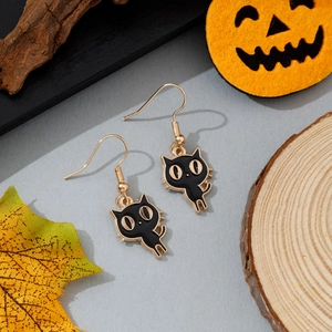 Détail de boucles d'oreilles chat noir émaillé avec décorations de citrouille et érable