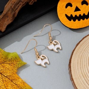 Gros plan de boucles d'oreilles chat d'Halloween avec bordure dorée sur décor citrouille