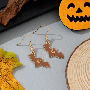 Détail des boucles d'oreilles chauve-souris avec visage sur fond festif d'Halloween