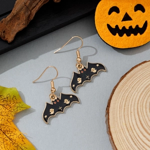 Détail de boucles d'oreilles chauve-souris en émail noir avec étoiles sur fond d'automne