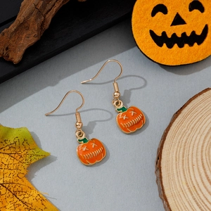 Détail de boucles d'oreilles citrouille orange avec motifs noirs sur fond bois rustique