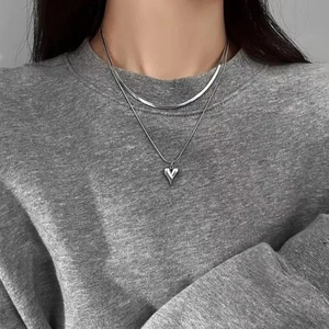 Dettaglio della collana a doppio strato con catena a serpente e ciondolo a cuore su modella