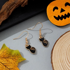 Détail de boucles d'oreilles chat noir et crochets dorés sur fond de fête d'Halloween