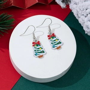 Detail of Christmas tree drop earrings with green enamel and red bow on festive background