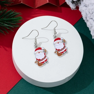 Close-up of Santa Claus hook earrings with festive red and green holiday background
