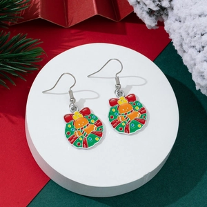 Detailed view of Christmas wreath earrings with red bows and bells on a festive background