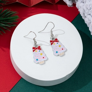 Detailed view of pink enamel Christmas tree earrings with holiday bow on white stand