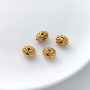 Macro detail of four gold hollow oval beads with vintage embossed floral patterns