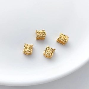 Detailed macro view of four hollow square golden charms with traditional beast carvings