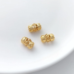Three gold-plated hollow lotus flower spacer beads for DIY jewelry making on white tray