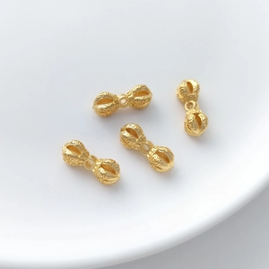 Detailed view of gold vajra beads with religious carvings for DIY jewelry making